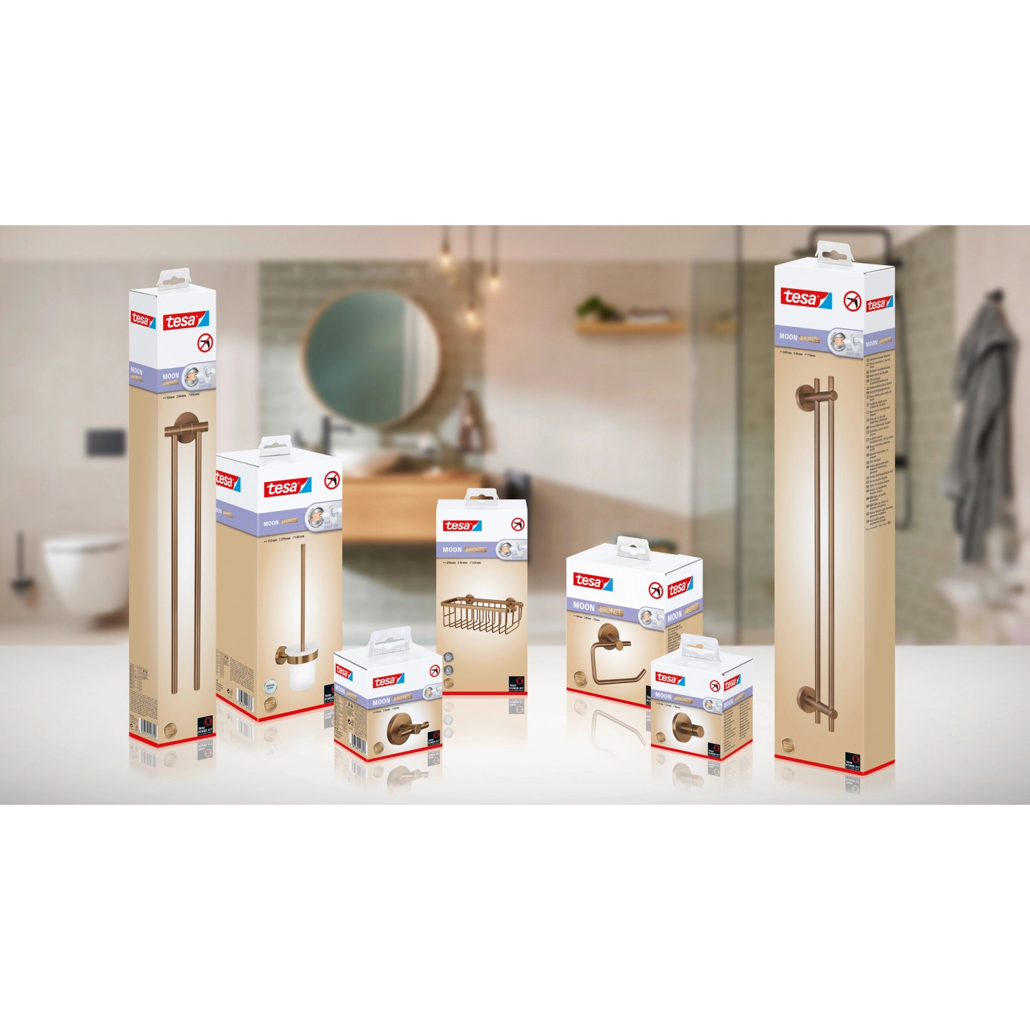 Tesa Moon WC-Garnitur in Bronze, verschiedene Badaccessoires in Verpackung im Hintergrund.