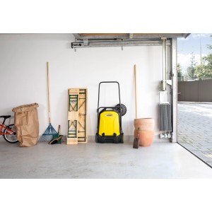 Kärcher Kehrmaschine S4, gelb/schwarz, mit Seitenbesen vor Garagenwand.
