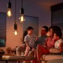 Familie im Wohnzimmer unter Philips Hue Filament Globe LED Lampen mit warmweissem Licht.