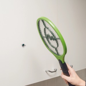 Grüne Gardigo Fliegenklatsche Bzzz in Aktion gegen Fliege an weißer Wand.