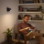 Philips Hue Buckram Spot, schwarz, mit Mann lesend im Sessel. Warmweißes Licht.