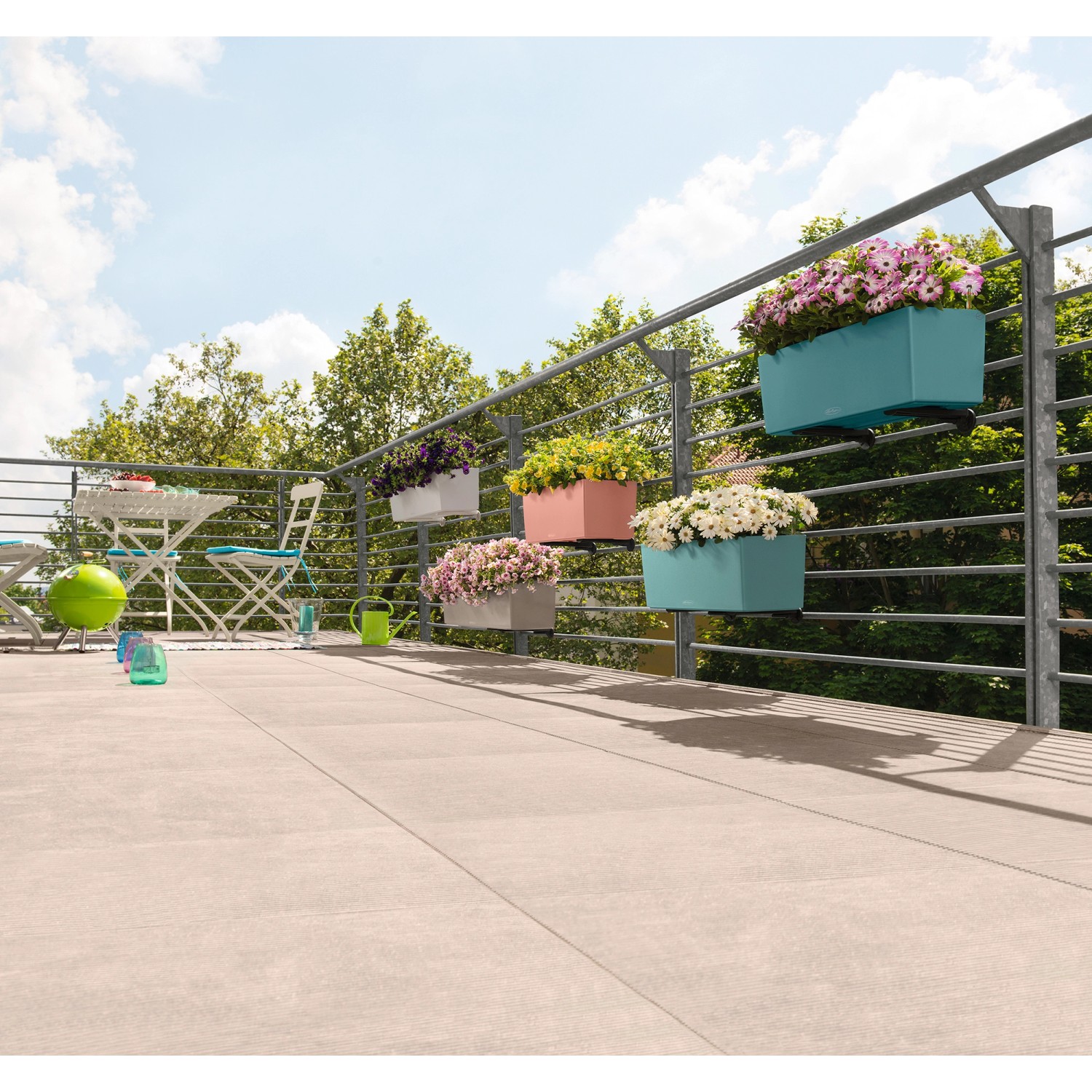 Verschiedene bepflanzte Lechuza Balconera Color Blumenkästen in Sandbraun und anderen Farben am Balkongeländer.