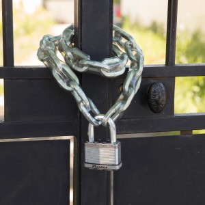 Master Lock Vorhängeschloss aus Stahl mit Kette an einem schwarzen Metalltor.