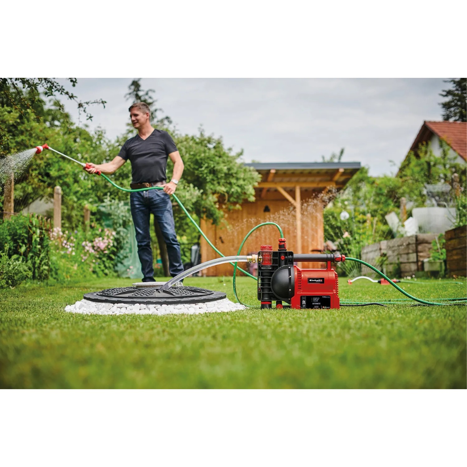 Einhell GE-AW 1142 FS Hauswasserautomat im Einsatz: Bewässerung im Garten mit roter Gartenpumpe.