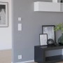 Weißer Eglo Connect Zigbee Wandschalter an grauer Wand im Wohnraum.