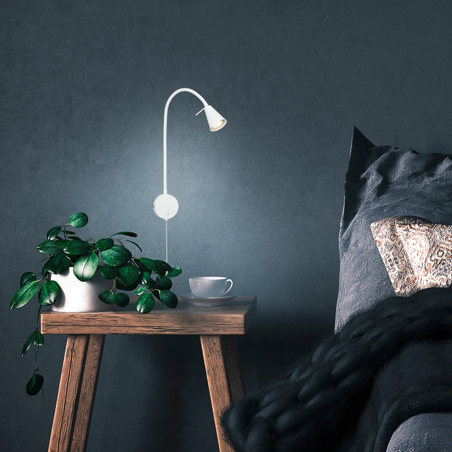 Briloner LED Bettleuchte Tusa, schwenkbar, warmweiß, montiert an blauer Wand über Nachttisch.