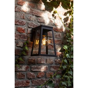 Anthrazitfarbene Lutec LED Solar-Wandleuchte Fia an einer Backsteinmauer mit Efeu.