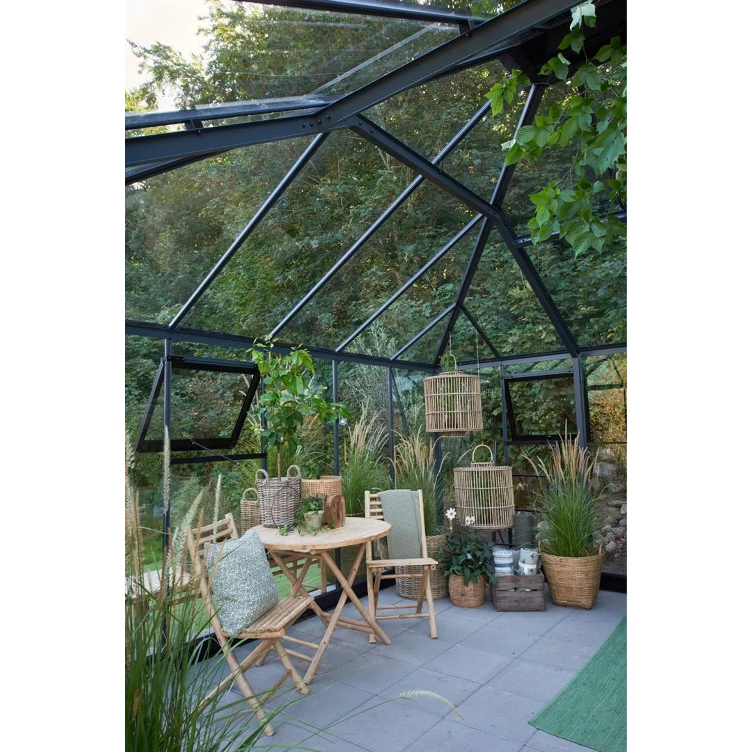 Juliana Gewächshaus Grand Oase 25, schwarz-anthrazit, mit Tisch und Stühlen im Inneren.