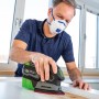 Mann schleift Holz mit LUX Akku-Multischleifer A-MS-20. Staubmaske und Staubfangbox für sauberes Arbeiten.