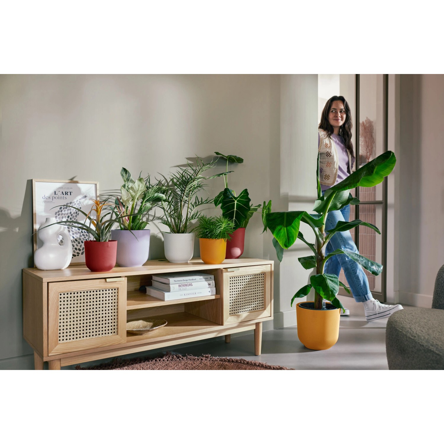 Elho Jazz Blumentopf, Ø 18,9 cm, warmes Gelb, mit Pflanzen auf einem Sideboard im Wohnzimmer.