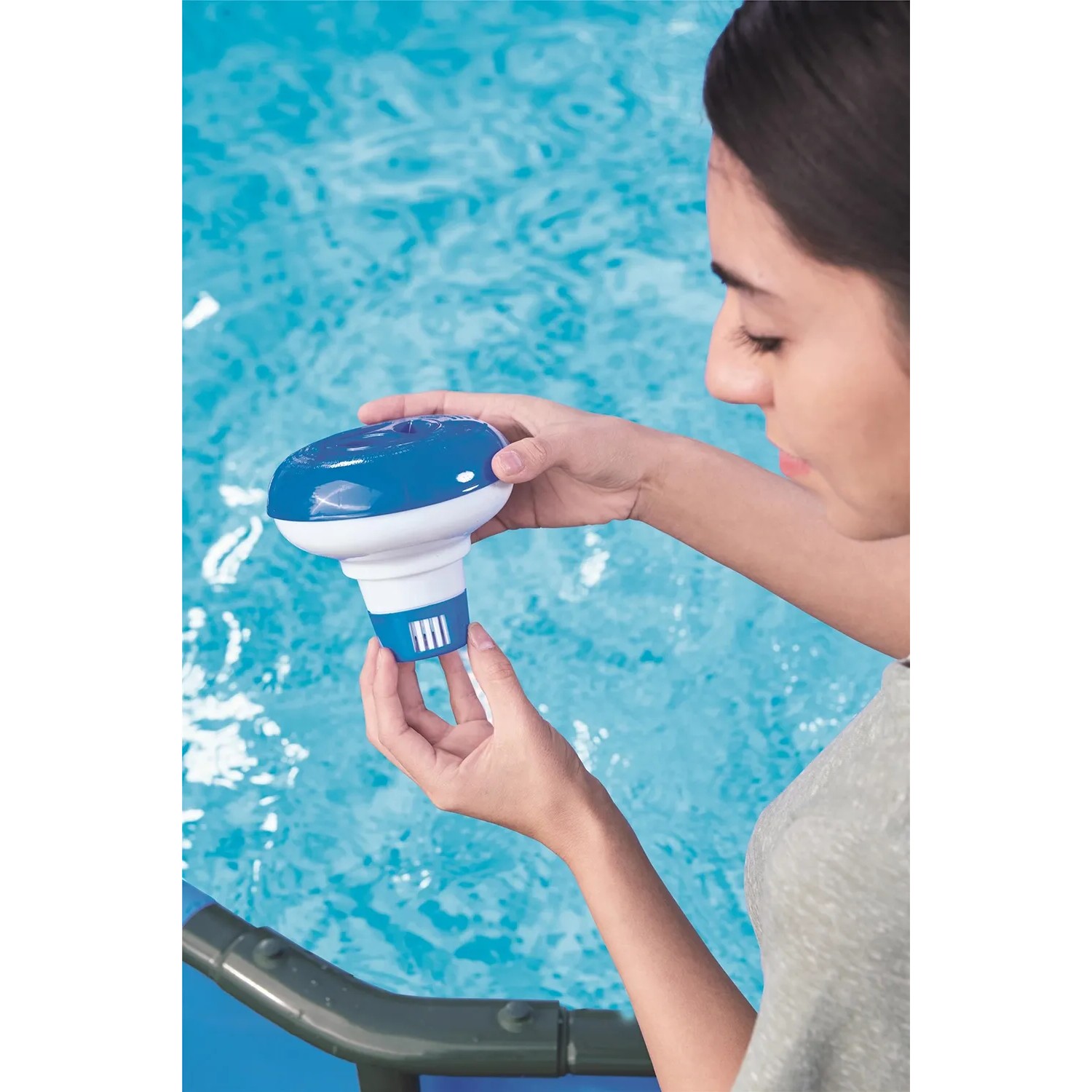 Frau hält Bestway Pool Dosierschwimmer für Chemikalien zur Poolpflege über Wasser.