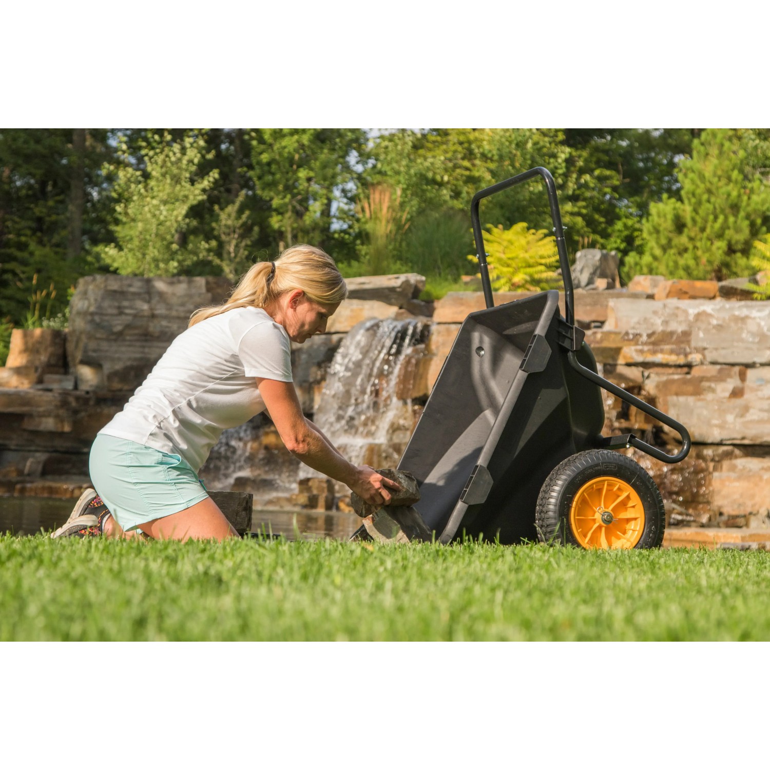 Polar Schubkarre Cub Cart, schwarz, beim Beladen mit Steinen im Garten.