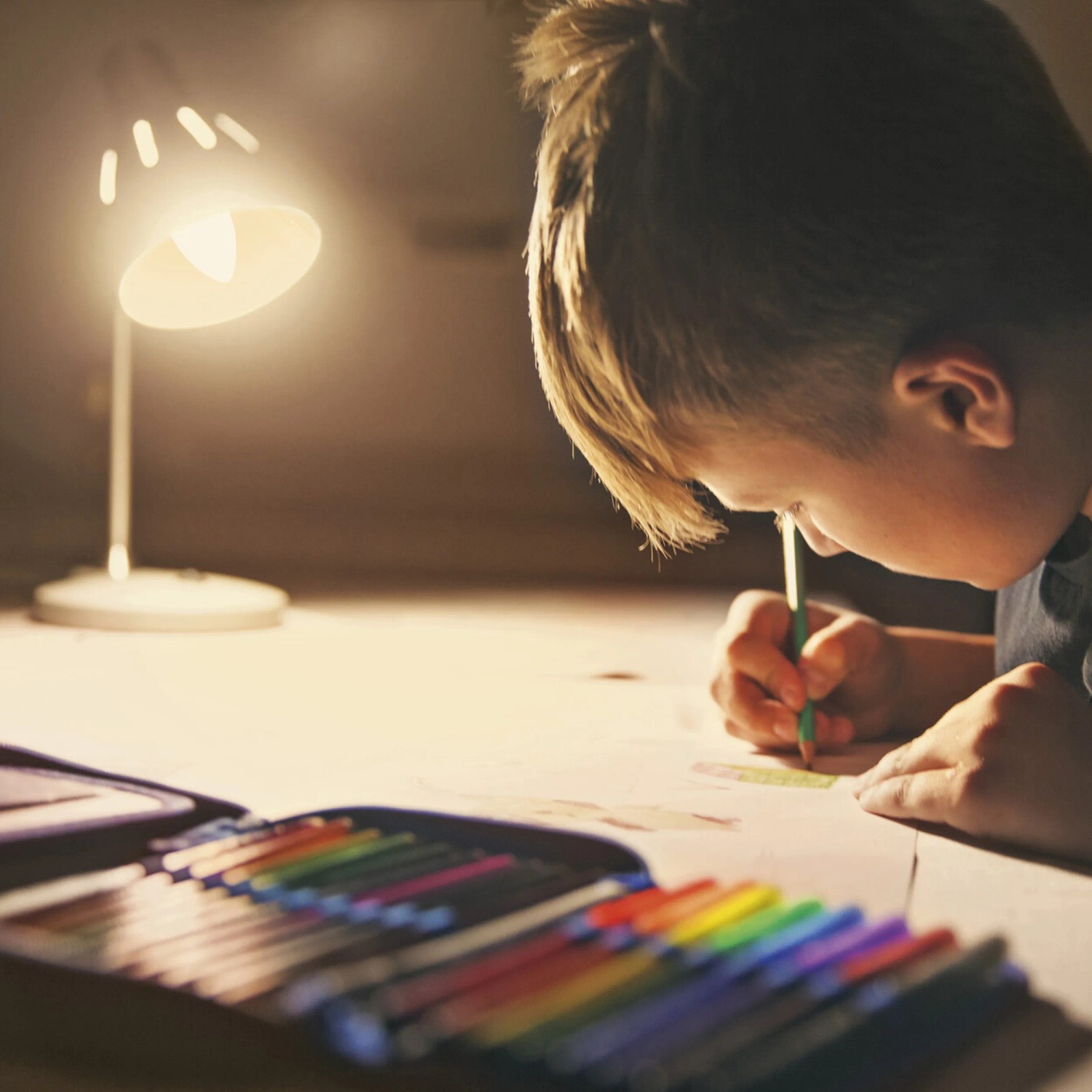 Kind malt im Licht einer Ledvance Sun@Home Smart+ Kerzenlampe. Smarte Leuchtmittel für besseres Wohlbefinden.