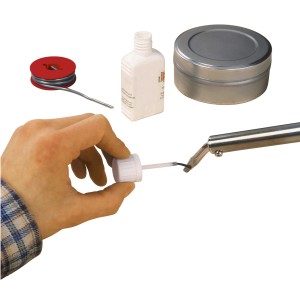 LUX Lötwasser 30ml mit Pinsel zum Auftragen auf eine Lötspitze, Zubehör im Hintergrund.