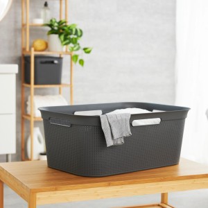 Anthrazitfarbener Rotho Wäschekorb Brisen (41 l) mit Lochmuster und Wäsche auf einem Holztisch.