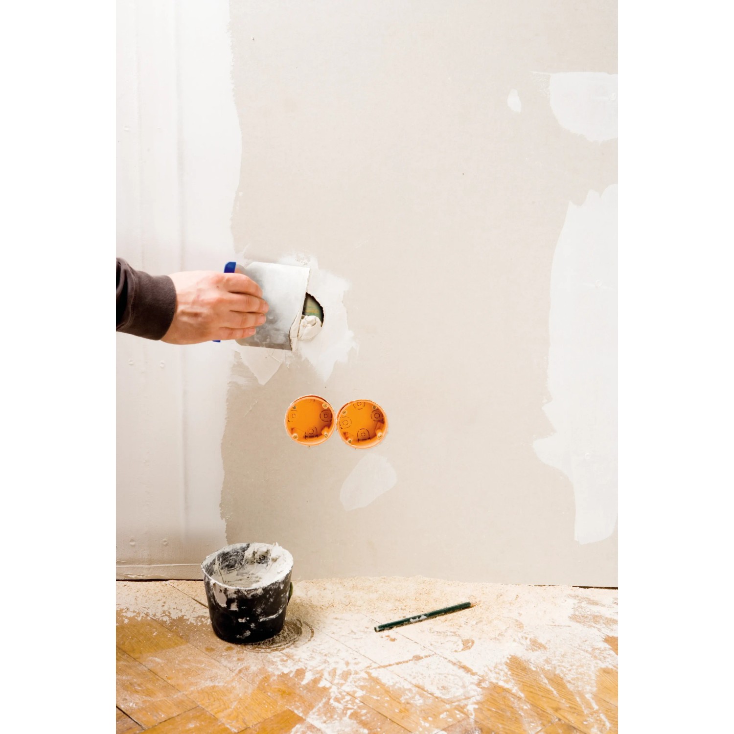 Handwerker spachtelt Wand mit Japanspachtel-Set von LUX. Werkzeug und Spachtelmasse im Einsatz.