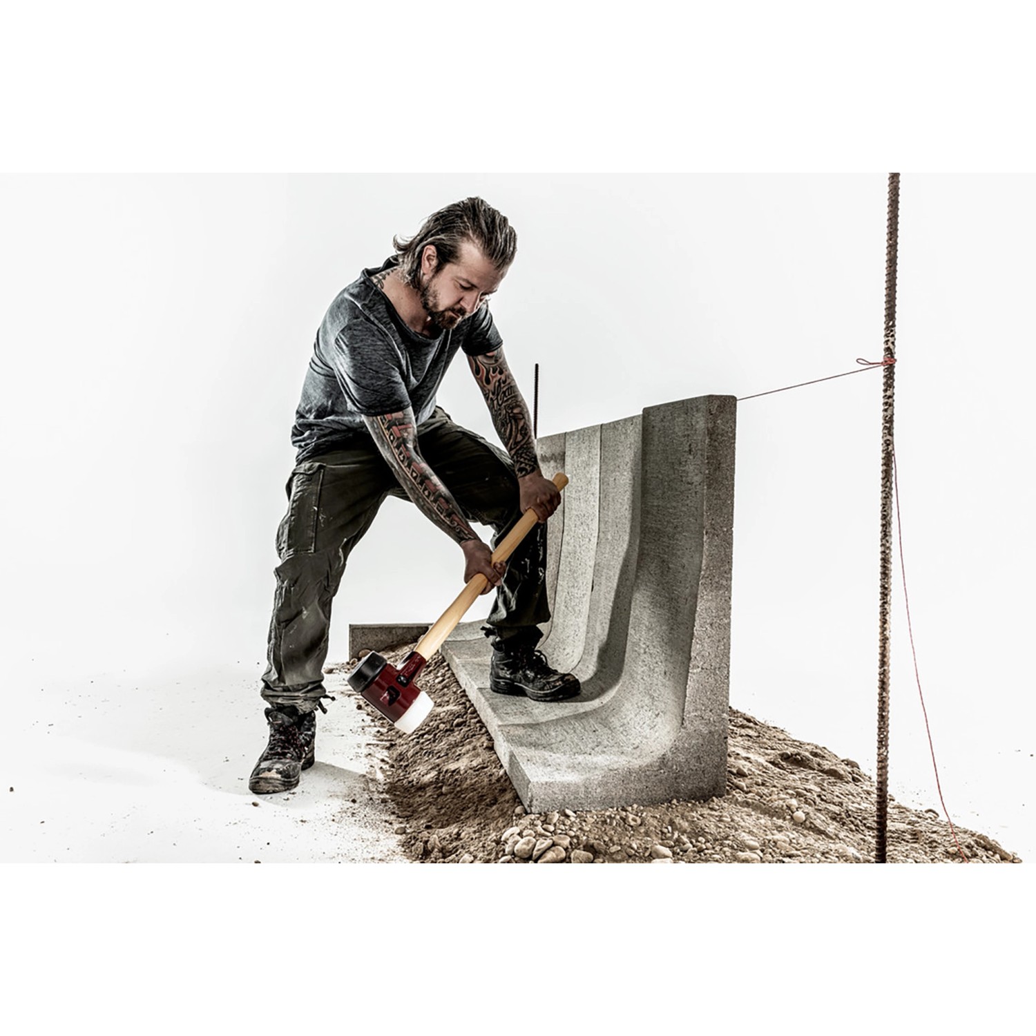 Mann arbeitet mit Halder Vorschlaghammer (Gummi/Superplastik) an einem Betonstein.