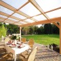 Skan Holz Terrassenüberdachung Ravenna aus Douglasie Nussbaum mit Polycarbonatplatten und Esstisch.
