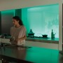 Frau in Küche mit Philips Hue Lightstrip Plus mit grüner Ambiente-Beleuchtung.