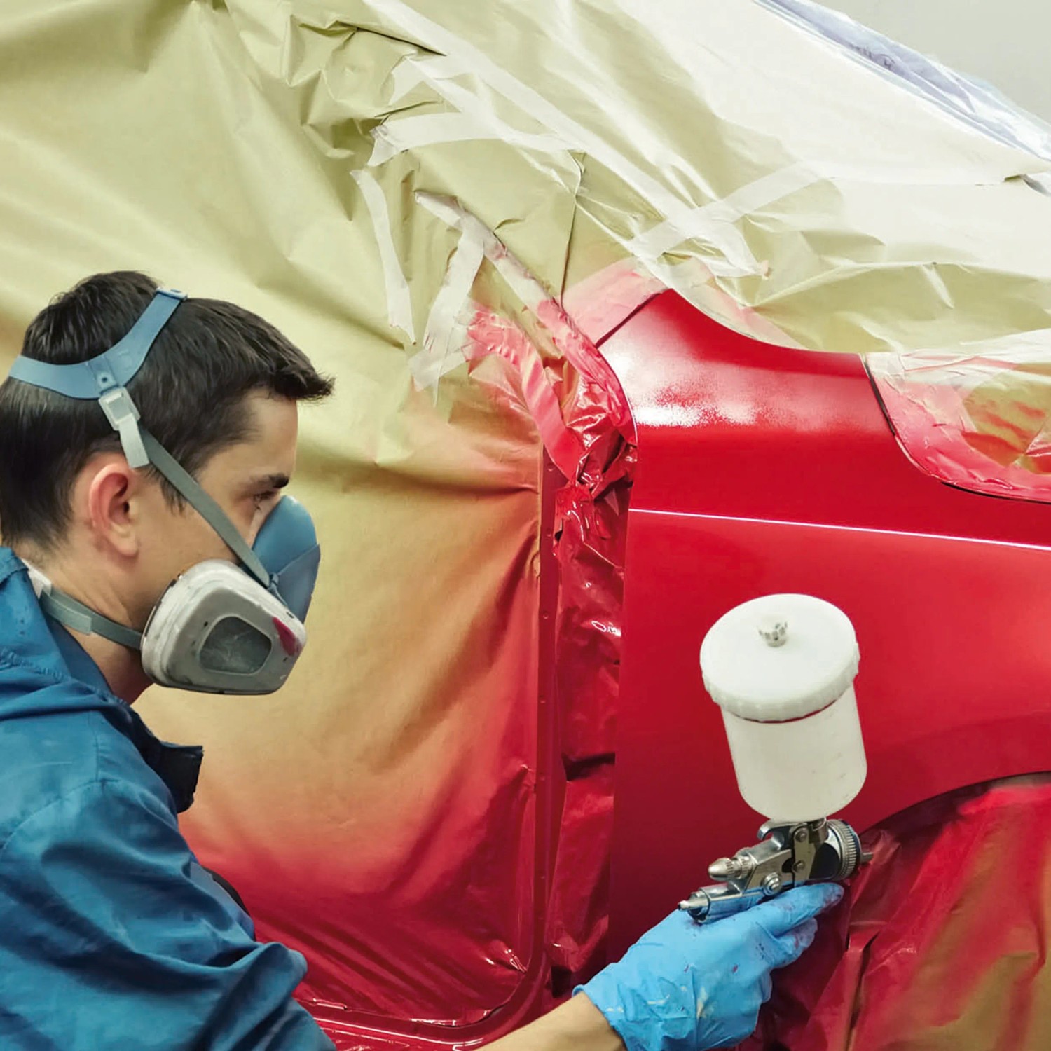 Lackieren eines roten Autos mit einem Einhell Kompressor (nicht enthalten).