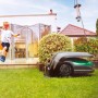 Robomow RoboHome Garage für RK-Modelle im Garten mit spielendem Kind.