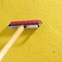 LUX Tapeten-Stachelwalze 15 cm mit Holzgriff zum Anreißen von Tapeten auf gelber Wand.