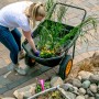 Schwarze Polar Schubkarre Cub Cart (127x71cm) mit Pflanzen im Garten.