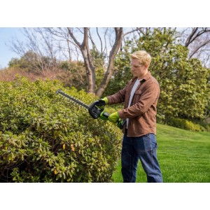 Mann trimmt Hecke mit Greenworks 56 cm Akku-Heckenschere Set. Für präzise Gartenschnitte.