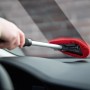 Autoscheibenreiniger mit Teleskopstiel und rotem Mikrofaser-Pad im Einsatz zur Reinigung einer Windschutzscheibe.