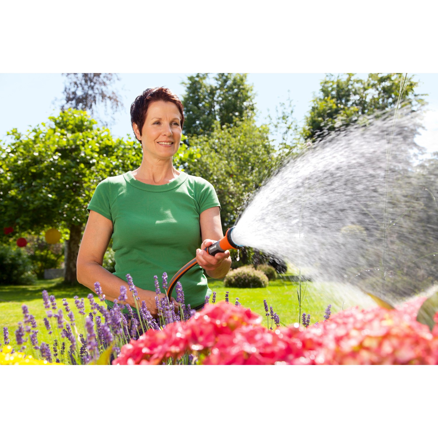 Frau bewässert Blumen mit Gardena Bewässerungsbrause im Garten.
