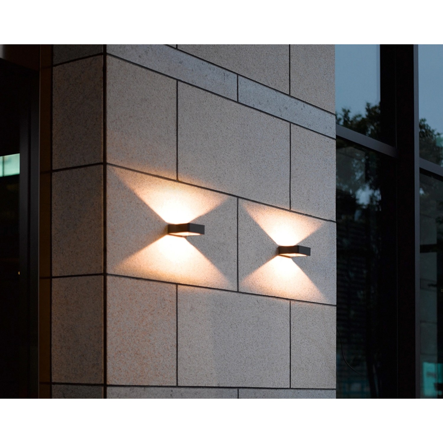 Zwei anthrazitfarbene Trio Reno LED-Außenwandleuchten an einer Steinwand mit Lichtkegeln nach oben und unten.