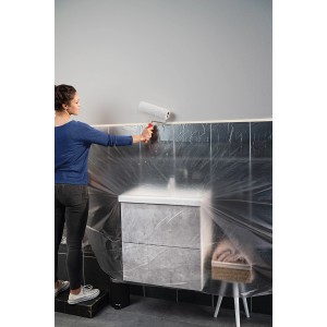 Frau streicht Wand mit Tesa Abdeckfolie Easy Cover Economy L. Schutz vor Farbspritzern.