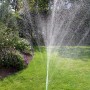 Gardena Schlauch-Regner (15 m, grün) im Einsatz, bewässert Rasenfläche mit feinem Sprühregen.