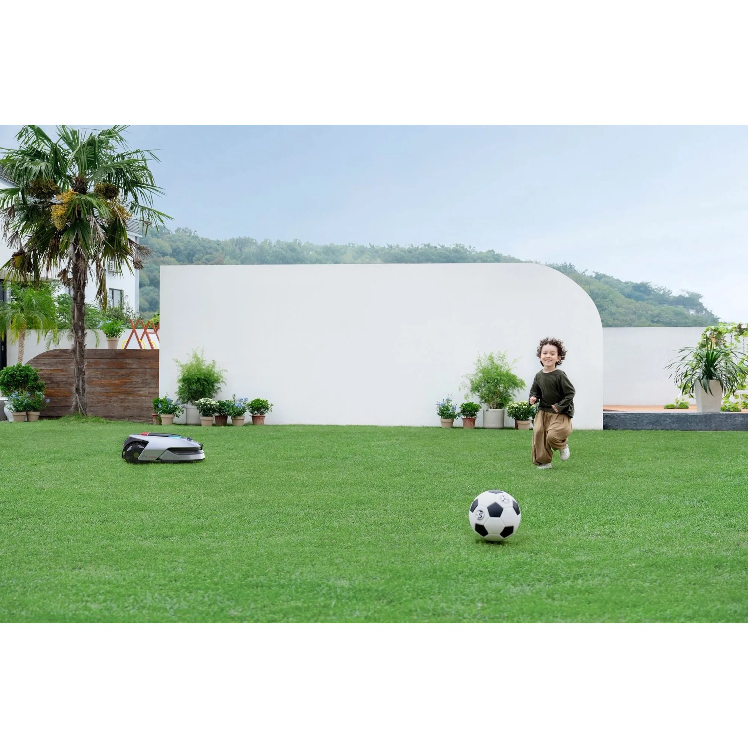 Dreame Mähroboter A2 2000 im Garten mit spielendem Kind und Fußball.