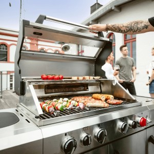 Enders Gasgrill Kansas II Pro: Silberner Grillwagen mit Speisen auf dem Grillrost und offener Haube.