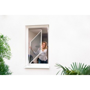 Frau montiert weißes Tesa Fliegengitter Alu Rahmen Comfort am Fenster.
