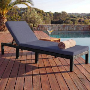 Anthrazitfarbene Poly-Rattan Sonnenliege mit grauen Kissen auf Holzdeck am Pool.
