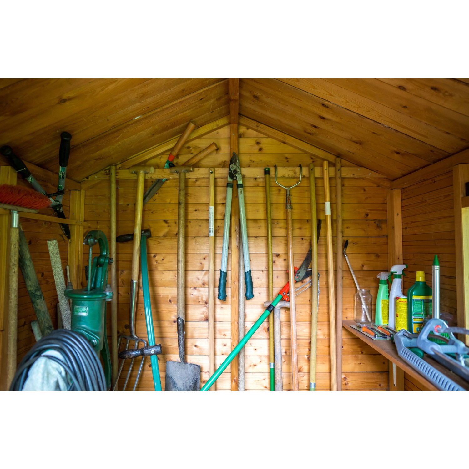 Holzschuppen Innenansicht mit Rauspund-Wänden und diversen Gartengeräten.