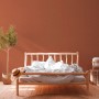 Schlafzimmer mit roter Vliestapete Uni Matt Strukturiert FSC® an der Wand.