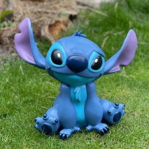 Blaue Stitch Gartenfigur aus Disney, sitzend auf Rasen. Dekorative Figur für Garten und Terrasse.