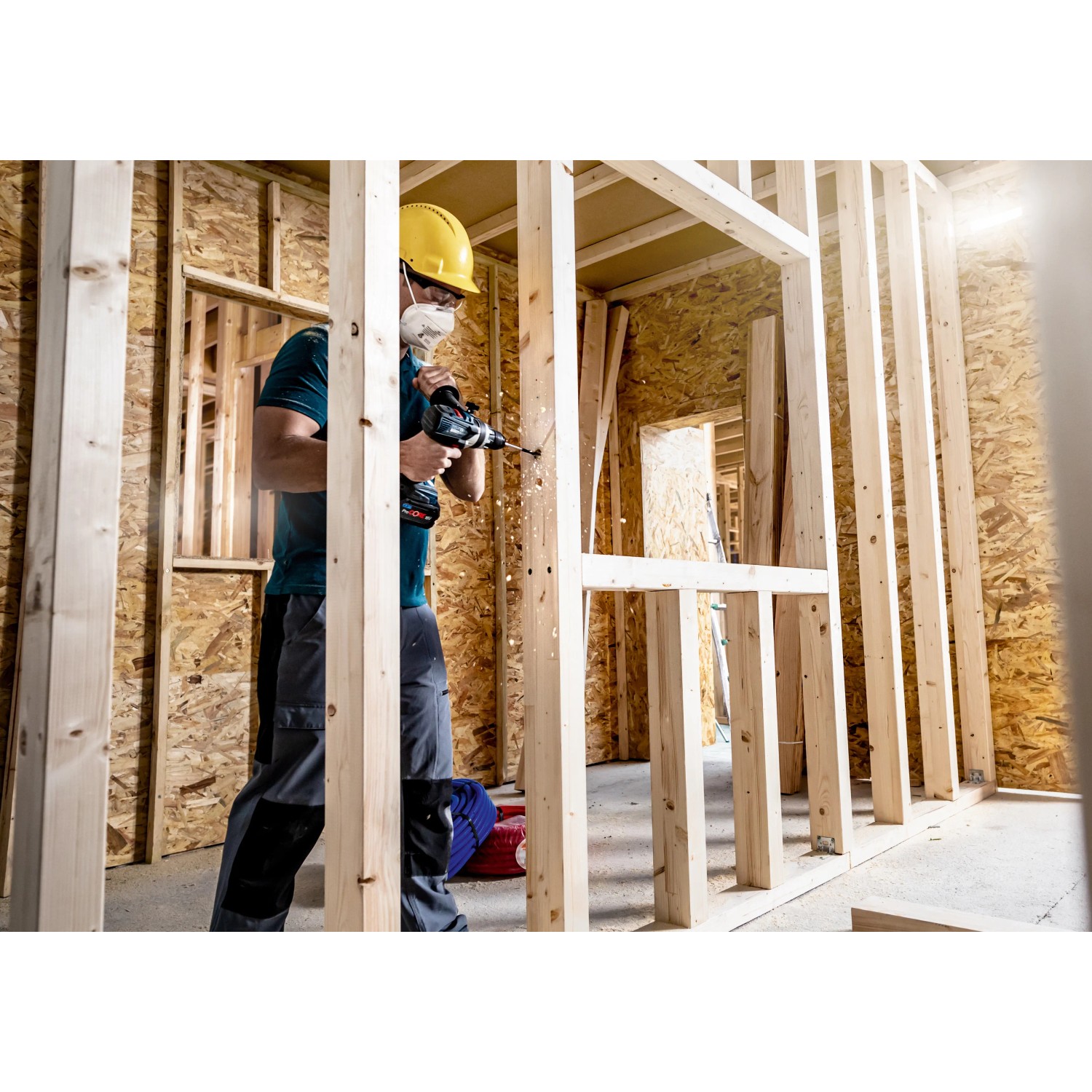Handwerker bohrt mit Bosch Expert Flachfräsbohrer Loch in Holzkonstruktion.