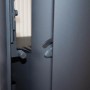 Detailaufnahme: Schwarzer Justus Kaminofen Mino 2.0 Stahl, Türgriff und Verriegelung im Fokus.