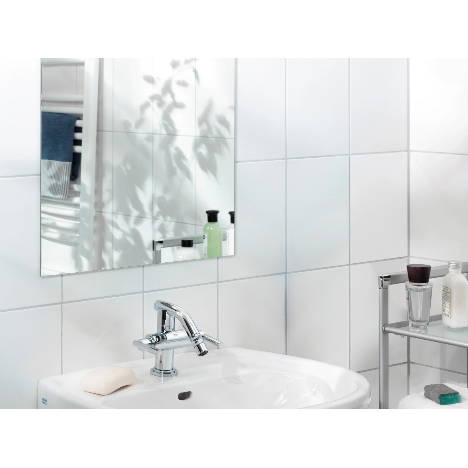 LUX Montageband im Badezimmer: Spiegel, Waschbecken und Armatur an weiß gefliester Wand.