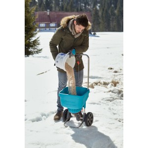 Mann befüllt Gardena Streuwagen XL im Winter mit Streugut. Vielseitig einsetzbarer Streuwagen.