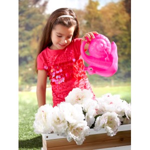 Mädchen gießt Blumen im AXI Blumenkasten (braun/weiß) mit einer rosa Gießkanne.