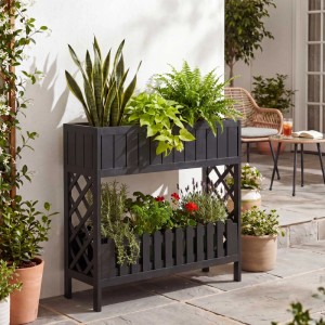 Schwarzes MCW Akazienholz Hochbeet mit zwei Pflanzebenen und Rankgitter, gefüllt mit Grünpflanzen und Blumen, auf Terrasse.