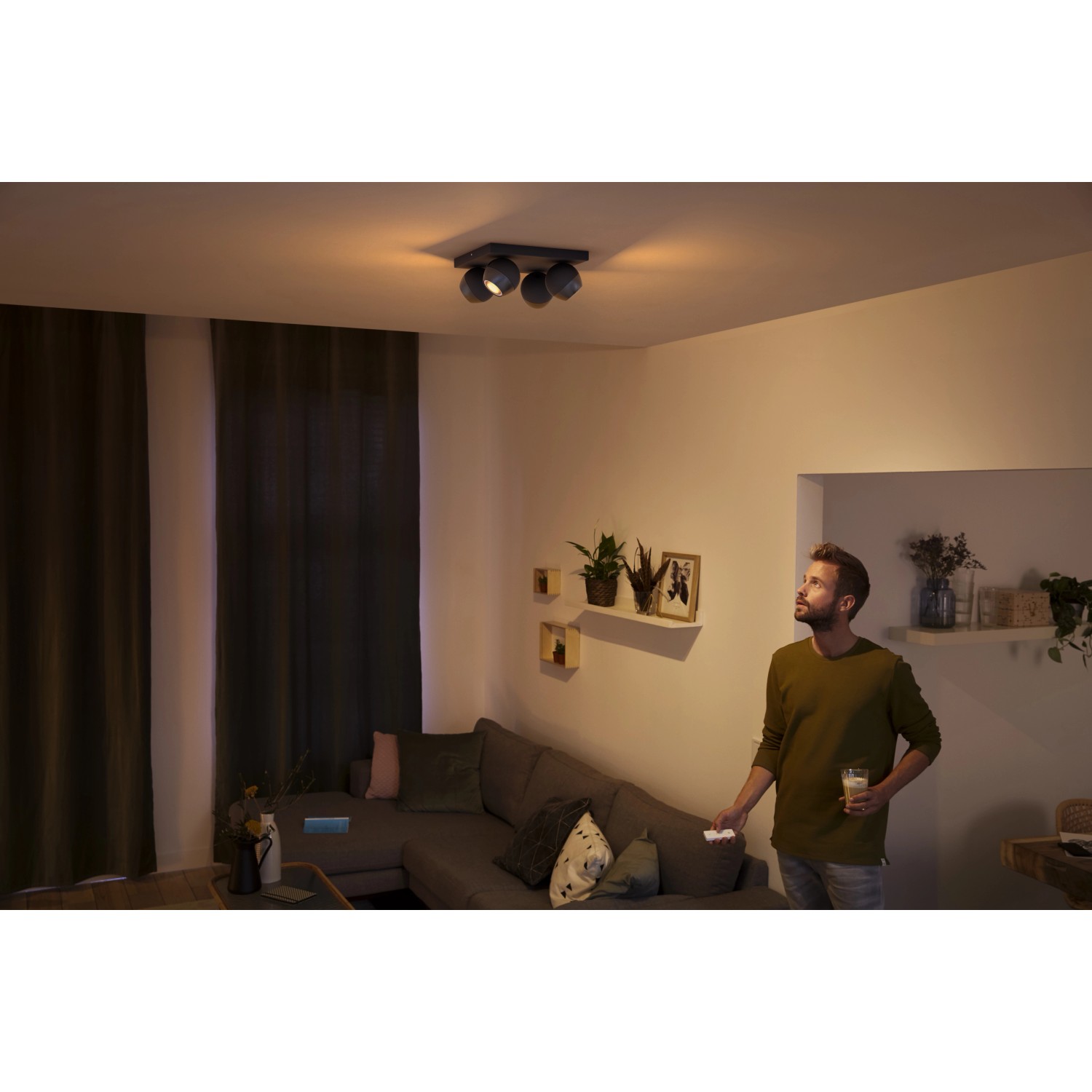 Schwarzer Philips Hue LED-Spot mit 4 Leuchten im Wohnraum, warmweißes Licht.