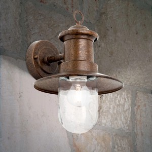 Orion Außen Wandleuchte Vintage-Braun, patiniert, mit klarem Glasschirm an Steinwand. Rustikale E27 Lampe für den Außenbereich.