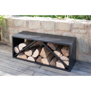 Schwarzes Westmann Kaminholzregal (104x34,5x40cm) mit Holzscheiten vor Steinmauer.