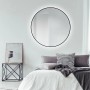 Runder DSK Design LED-Lichtspiegel Silver Globo, Ø 120 cm, mit schwarzem Rahmen an Schlafzimmerwand.